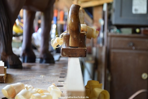 Ein Holzbrett wird mit einem Hobel bearbeitet.